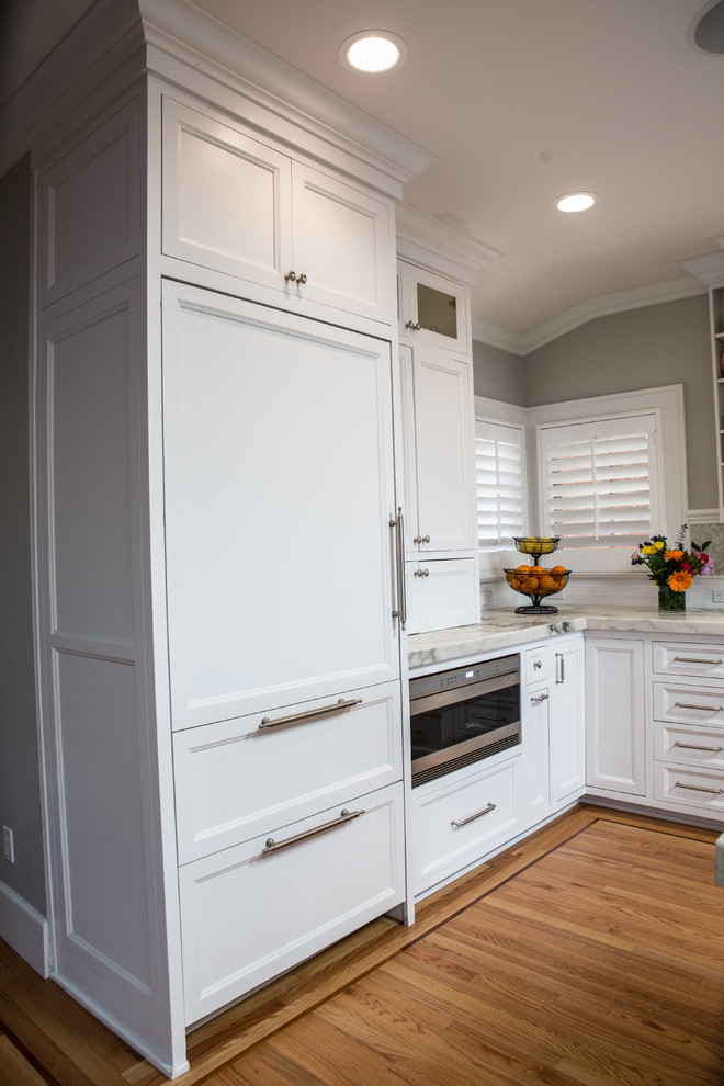 Foto di una cucina classica con lavello sottopiano, ante con riquadro incassato, ante bianche, top in marmo e pavimento in legno massello medio