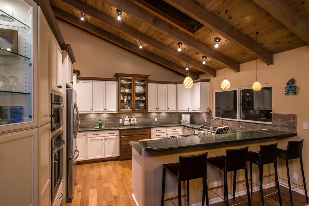 Inspiration for a mid-sized modern u-shaped medium tone wood floor eat-in kitchen remodel in San Diego with a double-bowl sink, recessed-panel cabinets, white cabinets, granite countertops, gray backsplash, stone tile backsplash and stainless steel appliances