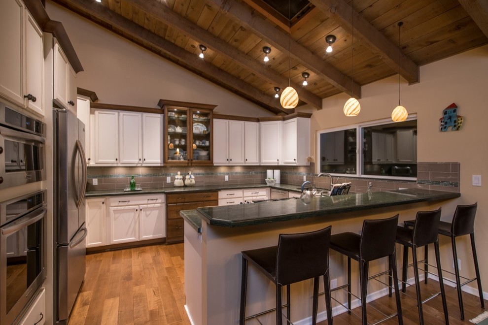 Example of a mid-sized minimalist u-shaped medium tone wood floor eat-in kitchen design in San Diego with a double-bowl sink, recessed-panel cabinets, white cabinets, granite countertops, gray backsplash, stone tile backsplash and stainless steel appliances