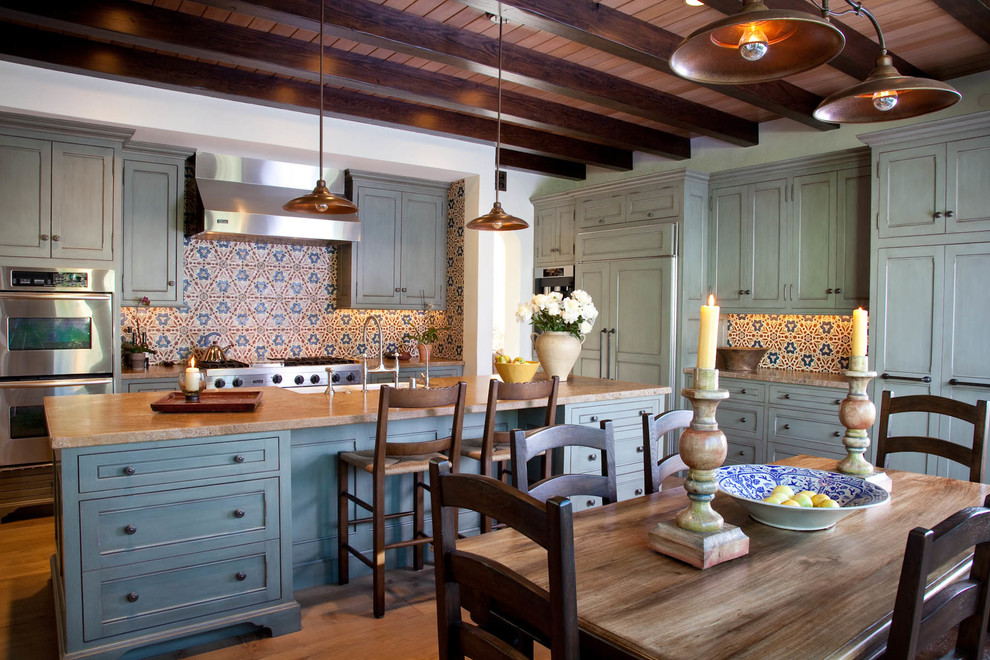 Immagine di un cucina con isola centrale mediterraneo con ante con riquadro incassato e parquet chiaro