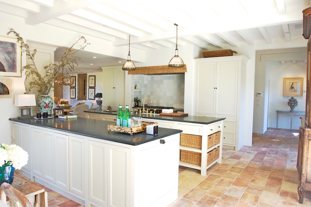Bild på ett mellanstort lantligt kök med öppen planlösning, med en rustik diskho, luckor med infälld panel, beige skåp, granitbänkskiva, blått stänkskydd, stänkskydd i keramik, integrerade vitvaror, klinkergolv i terrakotta och en köksö