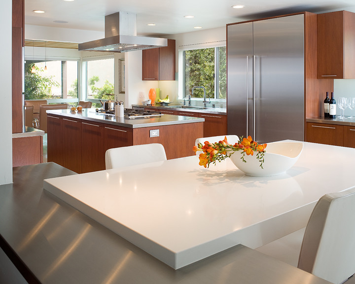 This is an example of a contemporary enclosed kitchen in San Diego with flat-panel cabinets, medium wood cabinets, composite countertops and stainless steel appliances.