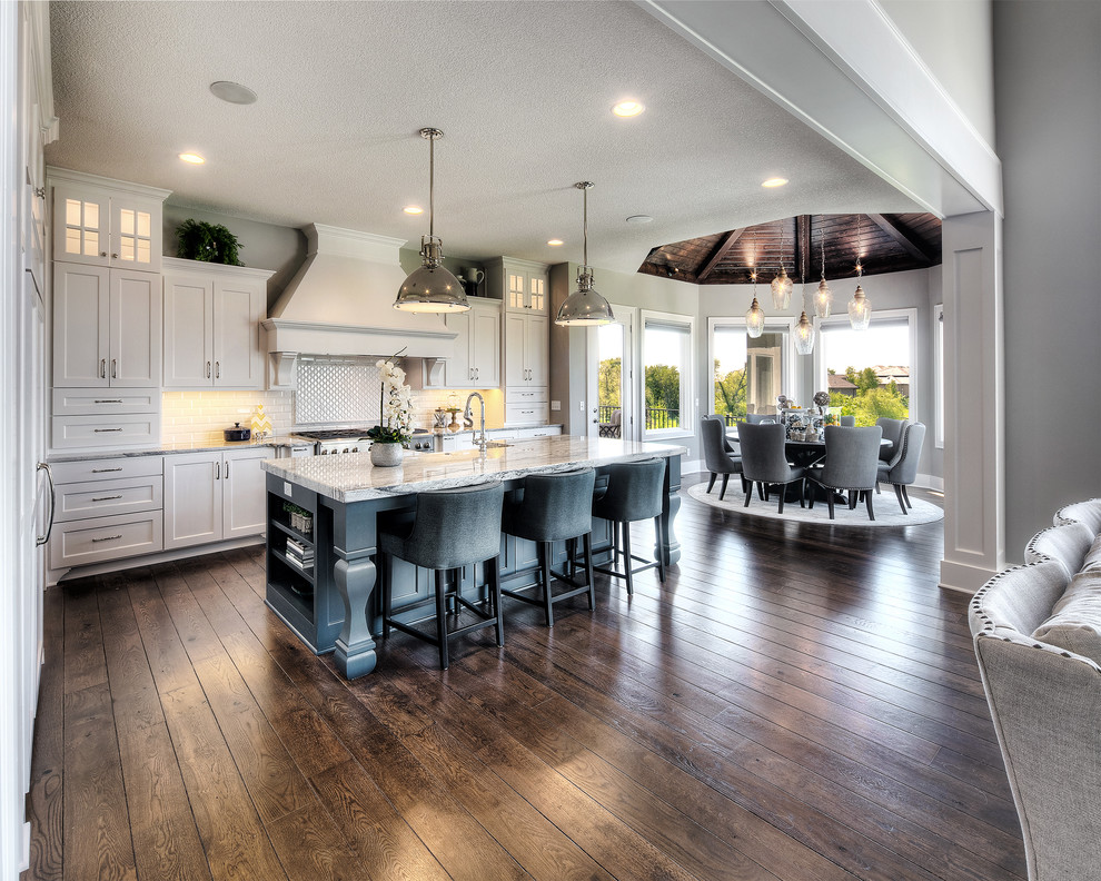 Eat-in kitchen - transitional l-shaped dark wood floor and brown floor eat-in kitchen idea in Kansas City with a farmhouse sink, shaker cabinets, white cabinets, white backsplash, paneled appliances, an island and beige countertops