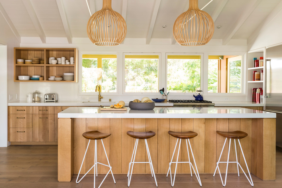 Exempel på ett modernt kök och matrum, med släta luckor, skåp i mellenmörkt trä, en köksö, vitt stänkskydd och rostfria vitvaror