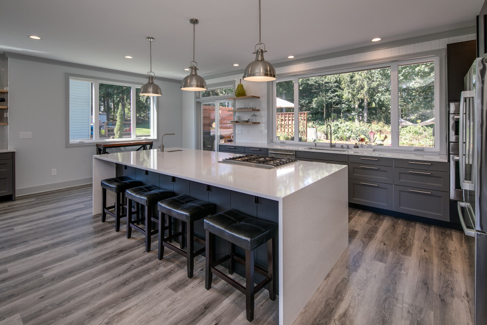 Inspiration for a medium sized contemporary galley open plan kitchen in Seattle with a submerged sink, flat-panel cabinets, grey cabinets, quartz worktops, white splashback, metro tiled splashback, stainless steel appliances, dark hardwood flooring, an island, grey floors and white worktops.