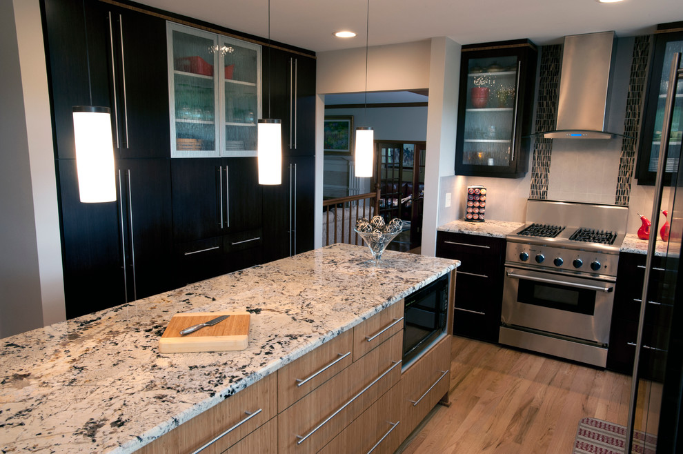 Inspiration for a mid-sized transitional galley light wood floor enclosed kitchen remodel in Milwaukee with an undermount sink, flat-panel cabinets, black cabinets, granite countertops, beige backsplash, mosaic tile backsplash and stainless steel appliances