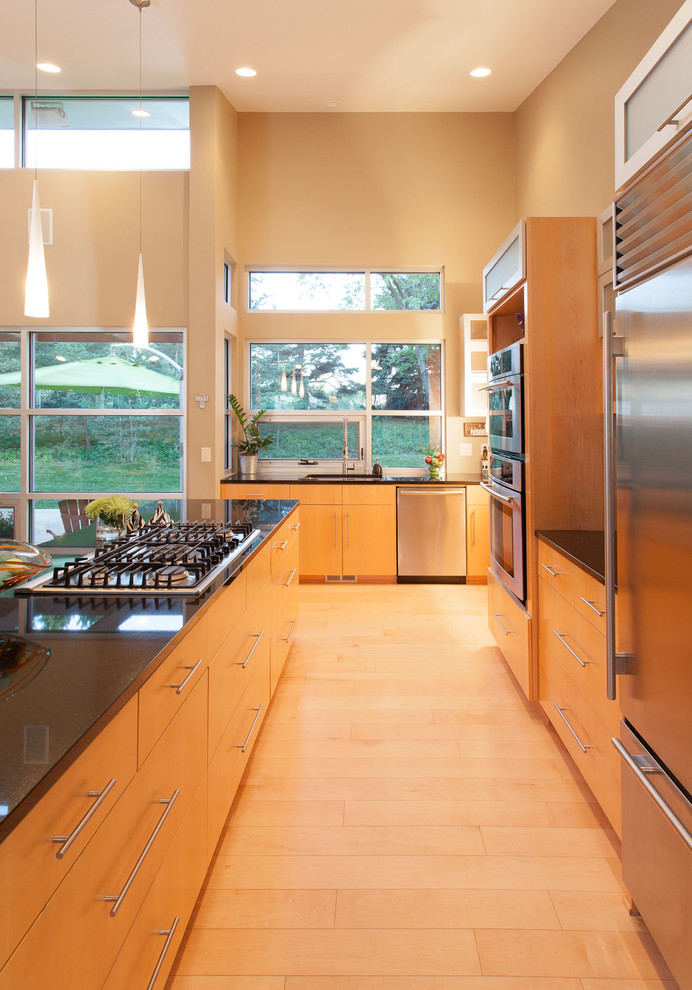 Exempel på ett modernt l-kök, med granitbänkskiva, rostfria vitvaror och släta luckor