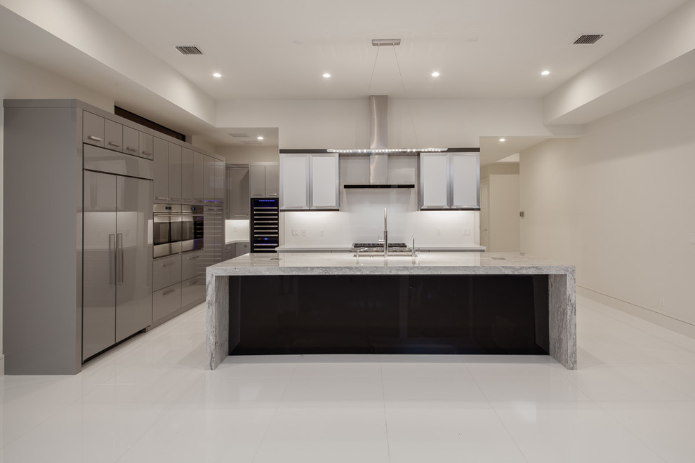 Inspiration for a large modern l-shaped open plan kitchen in Miami with a submerged sink, flat-panel cabinets, grey cabinets, engineered stone countertops, white splashback, glass sheet splashback, integrated appliances, an island, white floors and white worktops.