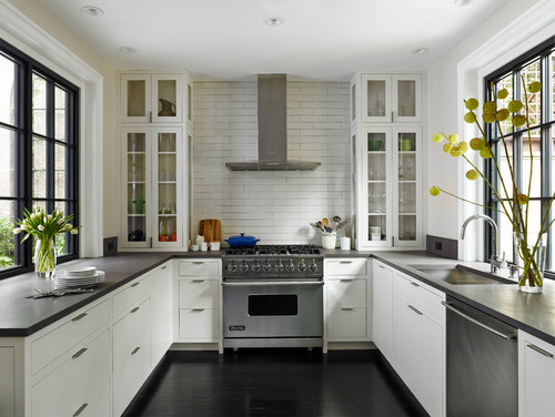 Kitchen & Bathroom Cabinets — white shaker kitchen with glass-front display towers, black stone countertops, subway-tile backsplash, and a pro stainless range.
