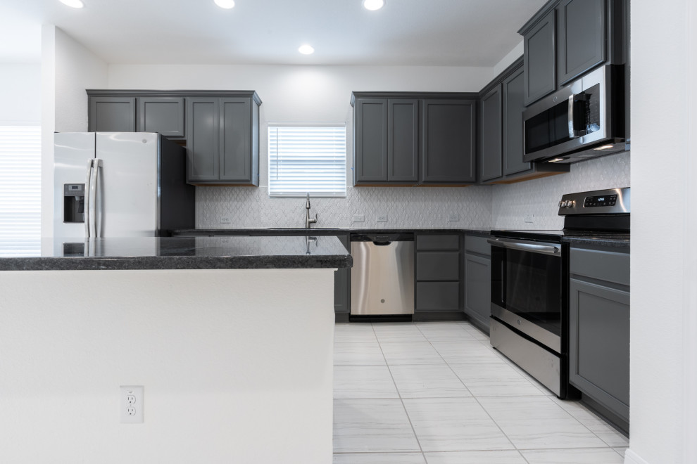 Idéer för att renovera ett stort amerikanskt svart svart kök, med en undermonterad diskho, luckor med infälld panel, grå skåp, granitbänkskiva, grått stänkskydd, stänkskydd i keramik, rostfria vitvaror, klinkergolv i keramik, en köksö och vitt golv