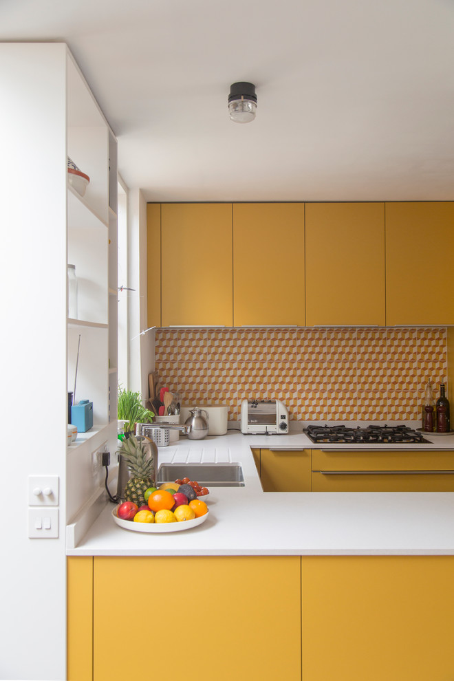 Bild på ett litet funkis kök, med släta luckor, gula skåp, en halv köksö, en integrerad diskho, bänkskiva i kvartsit, flerfärgad stänkskydd, stänkskydd i cementkakel, integrerade vitvaror och mörkt trägolv