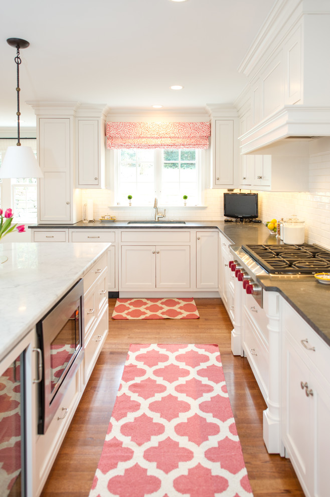 Klassische Küche in L-Form mit Kassettenfronten, weißen Schränken, Küchenrückwand in Weiß, Rückwand aus Metrofliesen, braunem Holzboden und Kücheninsel in Philadelphia