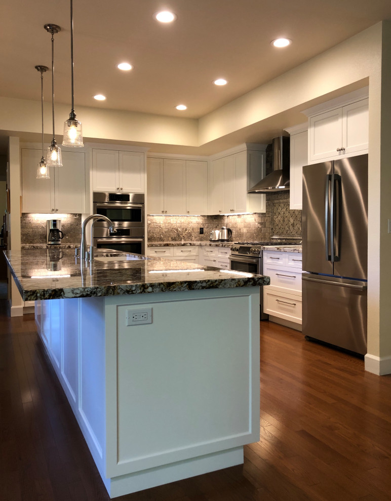Inspiration for a medium sized traditional l-shaped open plan kitchen in Sacramento with a submerged sink, shaker cabinets, white cabinets, granite worktops, grey splashback, porcelain splashback, stainless steel appliances, medium hardwood flooring, an island, brown floors and brown worktops.