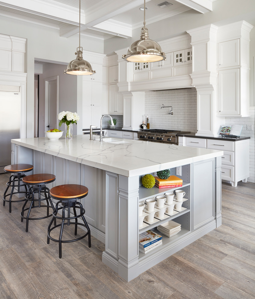 Open concept kitchen - large traditional l-shaped ceramic tile and brown floor open concept kitchen idea in Phoenix with an undermount sink, recessed-panel cabinets, white cabinets, quartz countertops, white backsplash, ceramic backsplash, stainless steel appliances and an island