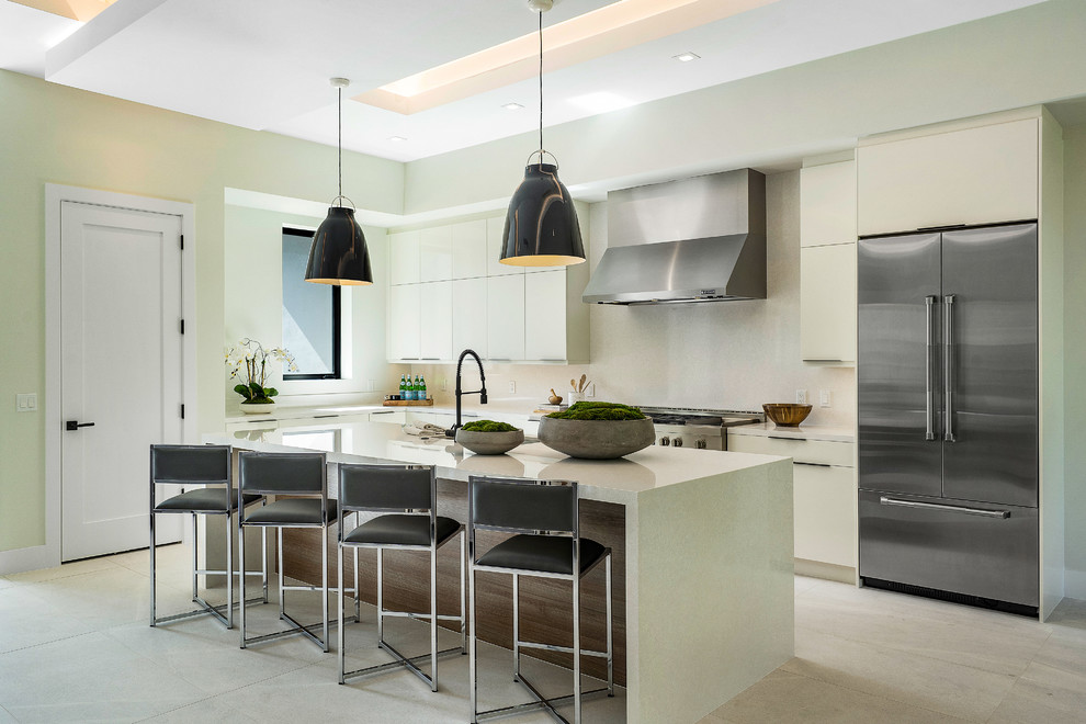 Design ideas for a contemporary grey and cream l-shaped kitchen in Miami with flat-panel cabinets, white cabinets, white splashback, stainless steel appliances, an island, grey floors and white worktops.