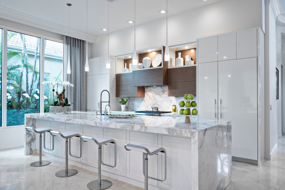Inspiration för stora moderna kök, med en undermonterad diskho, släta luckor, vita skåp, marmorbänkskiva, vitt stänkskydd, stänkskydd i sten, integrerade vitvaror, kalkstensgolv och en köksö