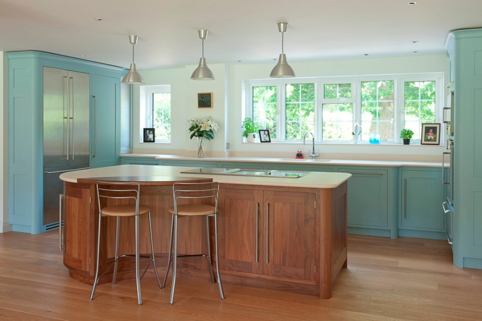 Modelo de cocina actual con armarios con paneles empotrados, puertas de armario azules, encimera de cuarzo compacto y electrodomésticos de acero inoxidable
