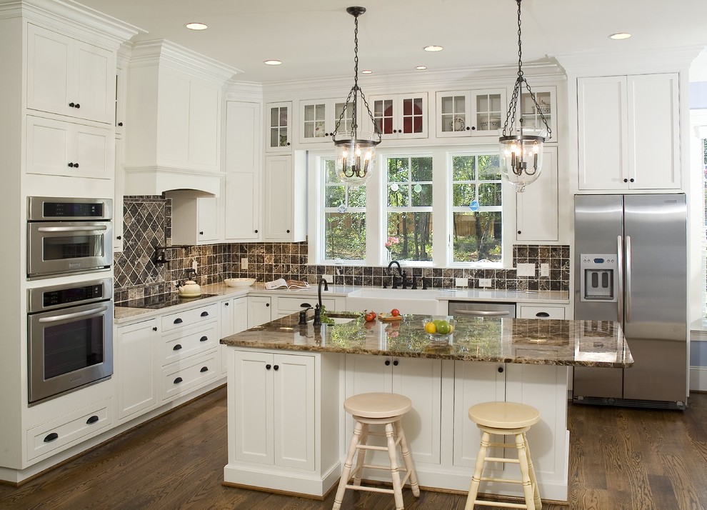 Foto på ett mellanstort vintage l-kök, med en rustik diskho, luckor med profilerade fronter, marmorbänkskiva, brunt stänkskydd, stänkskydd i stenkakel, rostfria vitvaror, mellanmörkt trägolv, en köksö och vita skåp