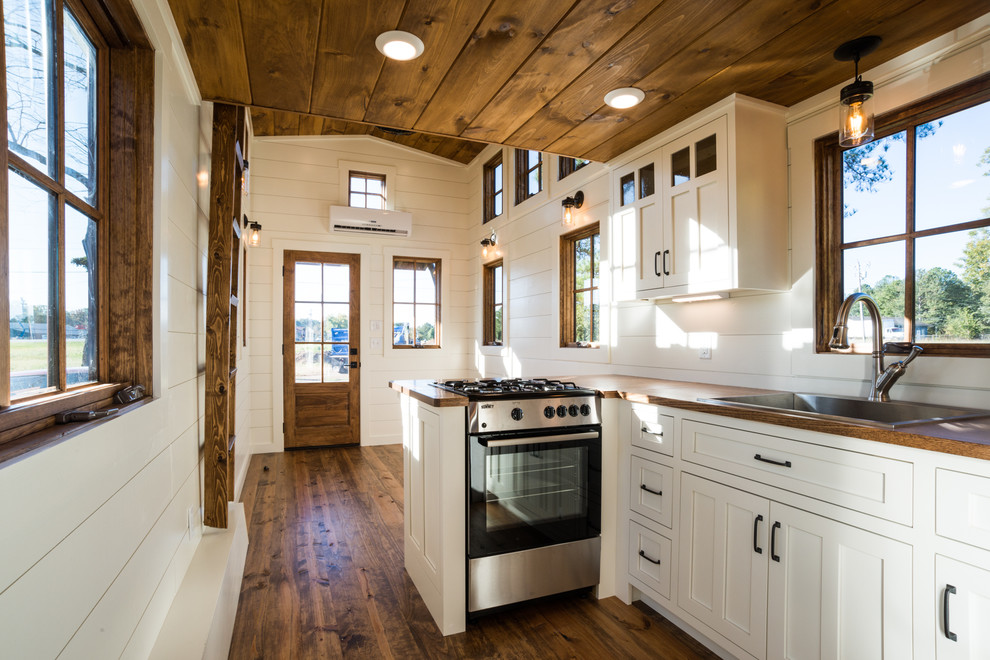 Foto på ett lantligt kök och matrum, med en nedsänkt diskho, skåp i shakerstil, vita skåp, träbänkskiva, rostfria vitvaror, mellanmörkt trägolv och brunt golv