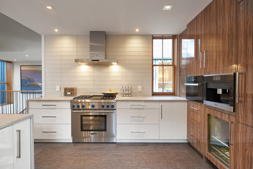 Mid-sized minimalist u-shaped dark wood floor and gray floor open concept kitchen photo in Grand Rapids with an undermount sink, flat-panel cabinets, medium tone wood cabinets, quartz countertops, white backsplash, glass tile backsplash, stainless steel appliances, a peninsula and beige countertops