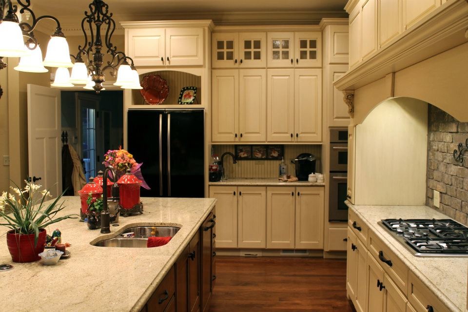 Imagen de cocina clásica con fregadero bajoencimera, armarios con paneles con relieve, puertas de armario blancas, encimera de granito, salpicadero blanco y electrodomésticos negros