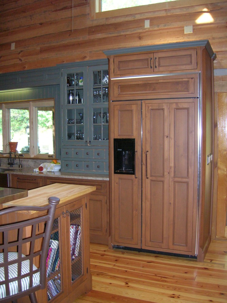 Bild på ett rustikt kök, med en rustik diskho, luckor med profilerade fronter, skåp i mellenmörkt trä, granitbänkskiva och rostfria vitvaror