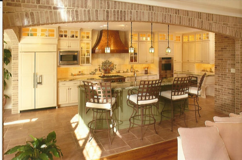 Modelo de cocina clásica con armarios con paneles con relieve, puertas de armario verdes, encimera de granito, salpicadero con mosaicos de azulejos y electrodomésticos de acero inoxidable