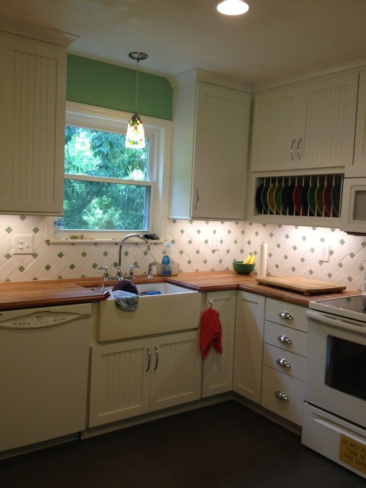 Klassisk inredning av ett kök, med en rustik diskho, skåp i shakerstil, vita skåp, träbänkskiva, flerfärgad stänkskydd, vita vitvaror och bambugolv