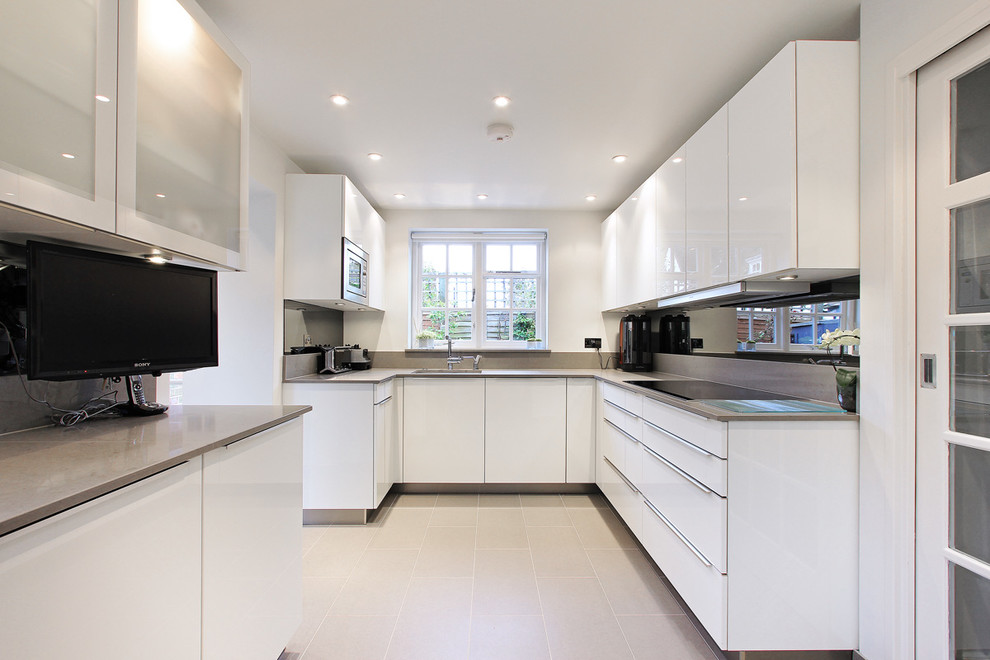 Moderne Küche mit flächenbündigen Schrankfronten, weißen Schränken und Rückwand aus Spiegelfliesen in London