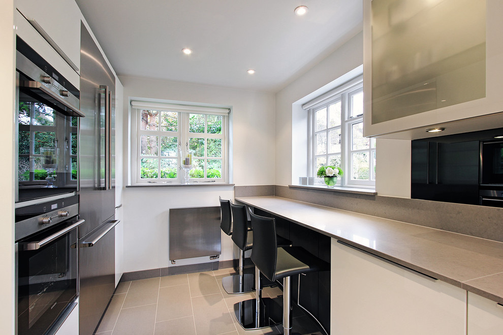 Immagine di una cucina design con ante di vetro e elettrodomestici in acciaio inossidabile