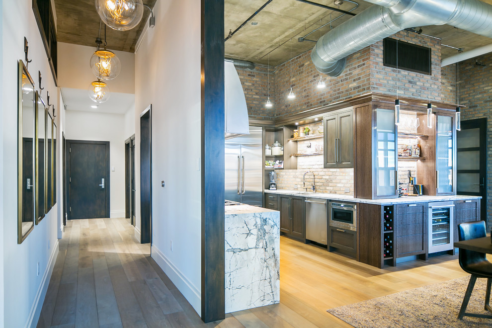 Photo of a medium sized industrial u-shaped kitchen/diner in Denver with a single-bowl sink, recessed-panel cabinets, dark wood cabinets, marble worktops, multi-coloured splashback, brick splashback, stainless steel appliances, medium hardwood flooring, no island and grey floors.