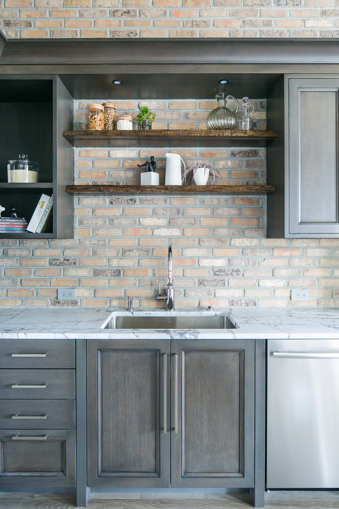 Foto på ett mellanstort industriellt kök, med en enkel diskho, luckor med infälld panel, skåp i mörkt trä, marmorbänkskiva, flerfärgad stänkskydd, stänkskydd i tegel, rostfria vitvaror, mellanmörkt trägolv och grått golv