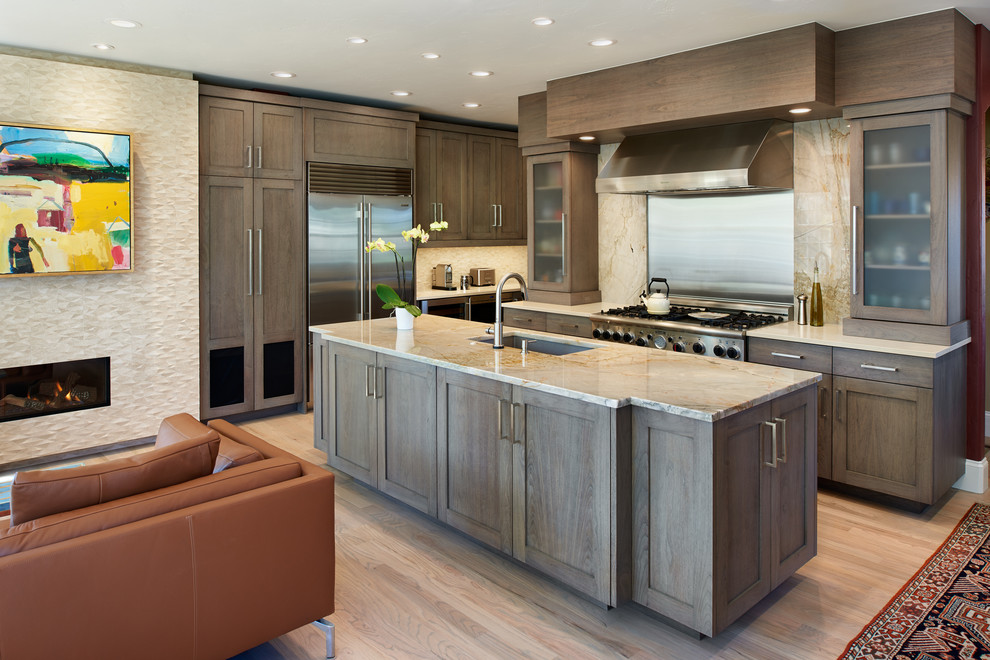 Example of a large transitional galley medium tone wood floor and multicolored floor eat-in kitchen design in Denver with an undermount sink, recessed-panel cabinets, gray cabinets, black backsplash, stone slab backsplash, stainless steel appliances, an island and beige countertops