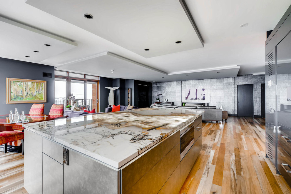 Inredning av ett modernt stort kök, med en undermonterad diskho, släta luckor, grå skåp, granitbänkskiva, integrerade vitvaror och en köksö