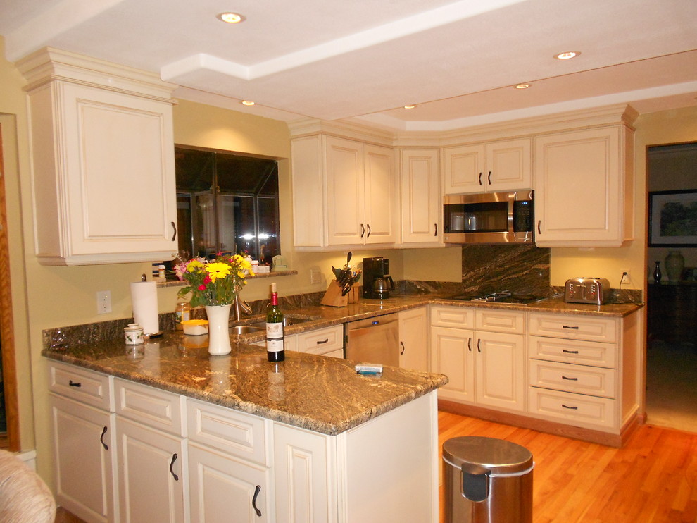 This is an example of a medium sized traditional u-shaped kitchen/diner in Denver with a submerged sink, raised-panel cabinets, beige cabinets, granite worktops, brown splashback, medium hardwood flooring and an island.