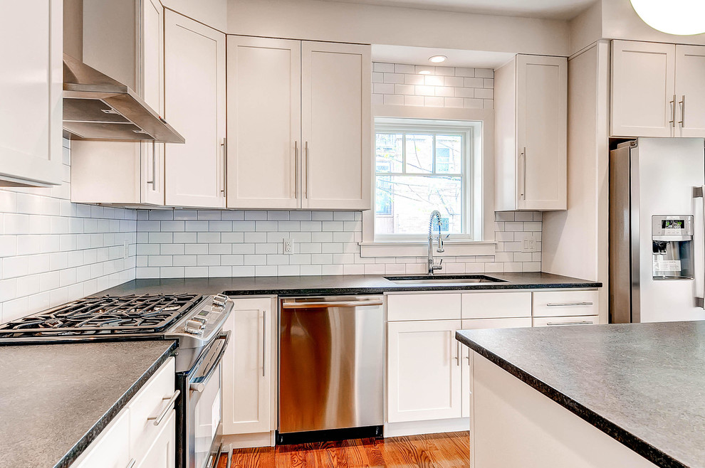 Inspiration for a mid-sized transitional l-shaped medium tone wood floor eat-in kitchen remodel in Denver with an undermount sink, shaker cabinets, white cabinets, granite countertops, white backsplash, ceramic backsplash, stainless steel appliances and an island