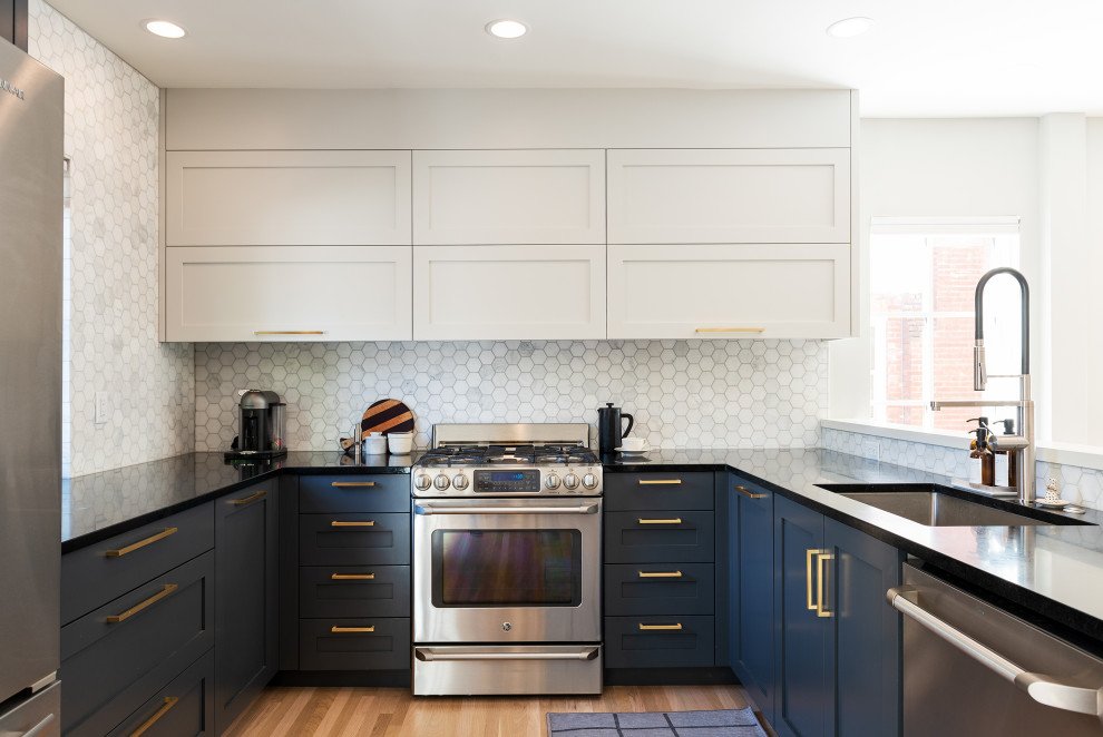 Inredning av ett klassiskt svart svart u-kök, med en undermonterad diskho, skåp i shakerstil, blå skåp, vitt stänkskydd, stänkskydd i mosaik, mellanmörkt trägolv, en halv köksö och brunt golv