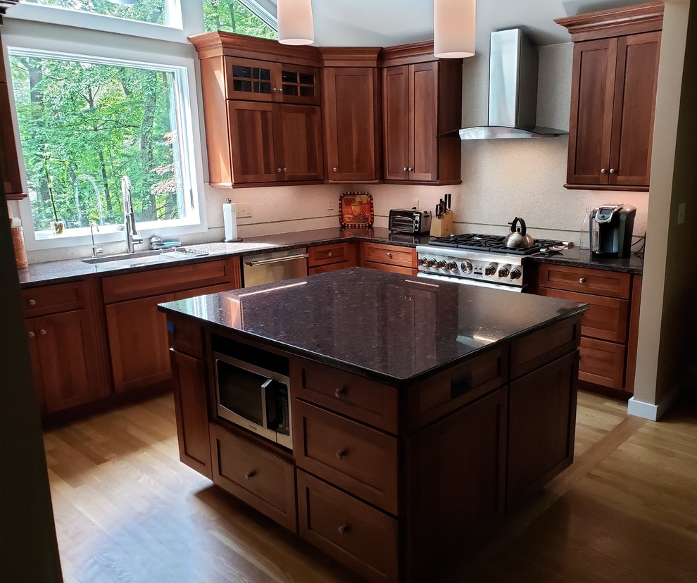 Exempel på ett avskilt, mellanstort klassiskt flerfärgad flerfärgat u-kök, med en undermonterad diskho, skåp i shakerstil, bruna skåp, granitbänkskiva, vitt stänkskydd, stänkskydd i porslinskakel, rostfria vitvaror, ljust trägolv, en köksö och gult golv