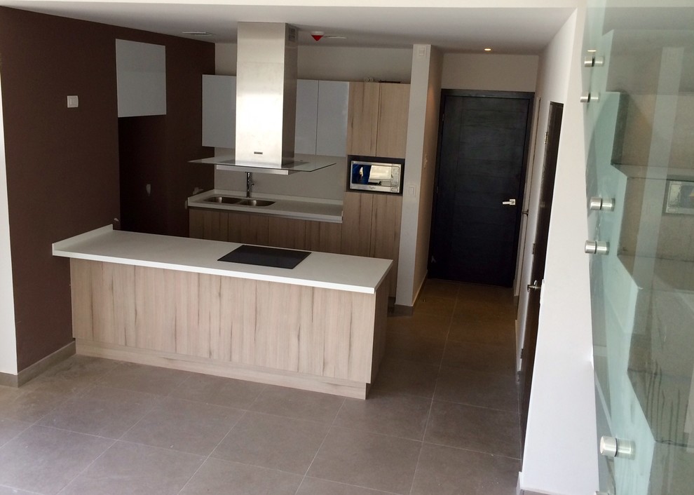 This is an example of a small modern galley kitchen/diner in Mexico City with a submerged sink, flat-panel cabinets, beige cabinets, composite countertops, stainless steel appliances, porcelain flooring and a breakfast bar.