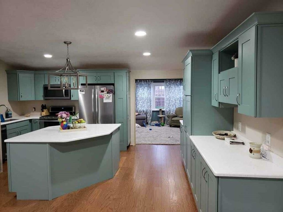 Inredning av ett eklektiskt stort vit vitt kök, med en undermonterad diskho, luckor med infälld panel, blå skåp, bänkskiva i koppar, rostfria vitvaror, ljust trägolv, en köksö och gult golv