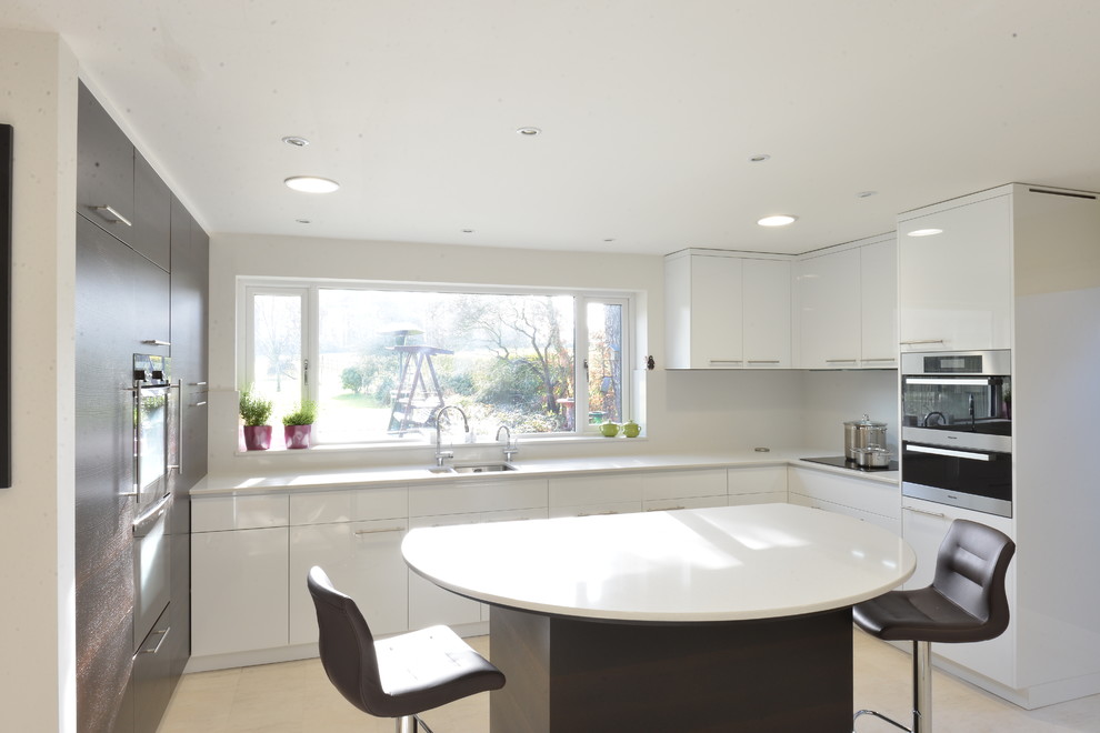 Foto på ett mellanstort funkis u-kök, med en undermonterad diskho, släta luckor, vita skåp, bänkskiva i kvartsit, vitt stänkskydd, klinkergolv i keramik, en köksö och rostfria vitvaror