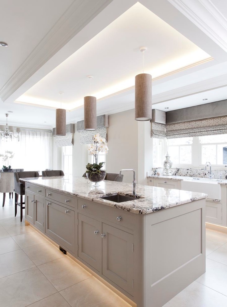 This is an example of a large traditional open plan kitchen in Other with an integrated sink, beaded cabinets, grey cabinets, granite worktops, beige splashback, metro tiled splashback, integrated appliances, ceramic flooring and an island.