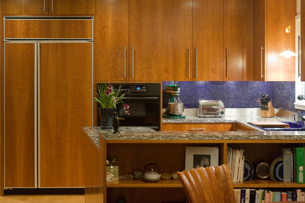 Moderne Wohnküche in U-Form mit Triple-Waschtisch, flächenbündigen Schrankfronten, Granit-Arbeitsplatte, Küchenrückwand in Blau, Rückwand aus Glasfliesen, Küchengeräten aus Edelstahl und hellbraunen Holzschränken in Washington, D.C.