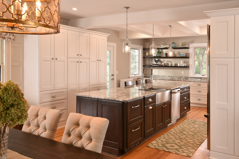 Mid-sized elegant galley medium tone wood floor eat-in kitchen photo in Other with a farmhouse sink, recessed-panel cabinets, white cabinets, stainless steel appliances, an island, granite countertops, white backsplash and subway tile backsplash