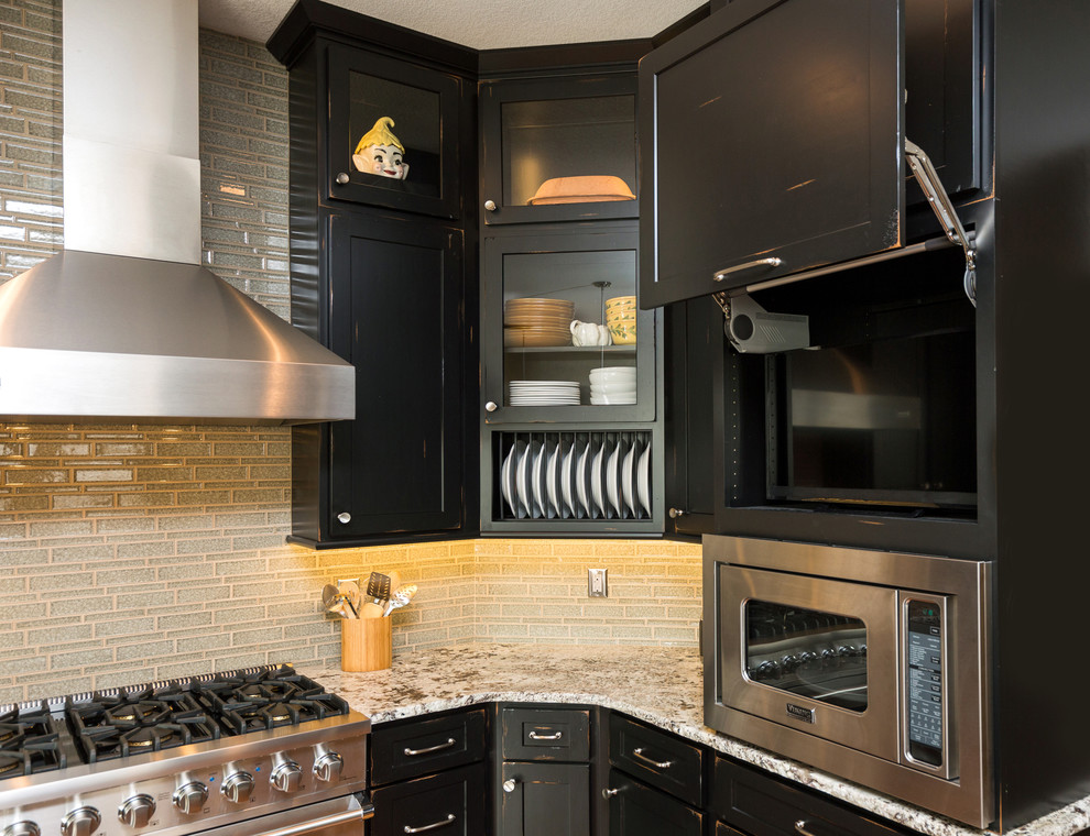 Inredning av ett klassiskt stort kök med öppen planlösning, med en enkel diskho, luckor med infälld panel, svarta skåp, granitbänkskiva, grått stänkskydd, stänkskydd i glaskakel, rostfria vitvaror, mellanmörkt trägolv och en köksö
