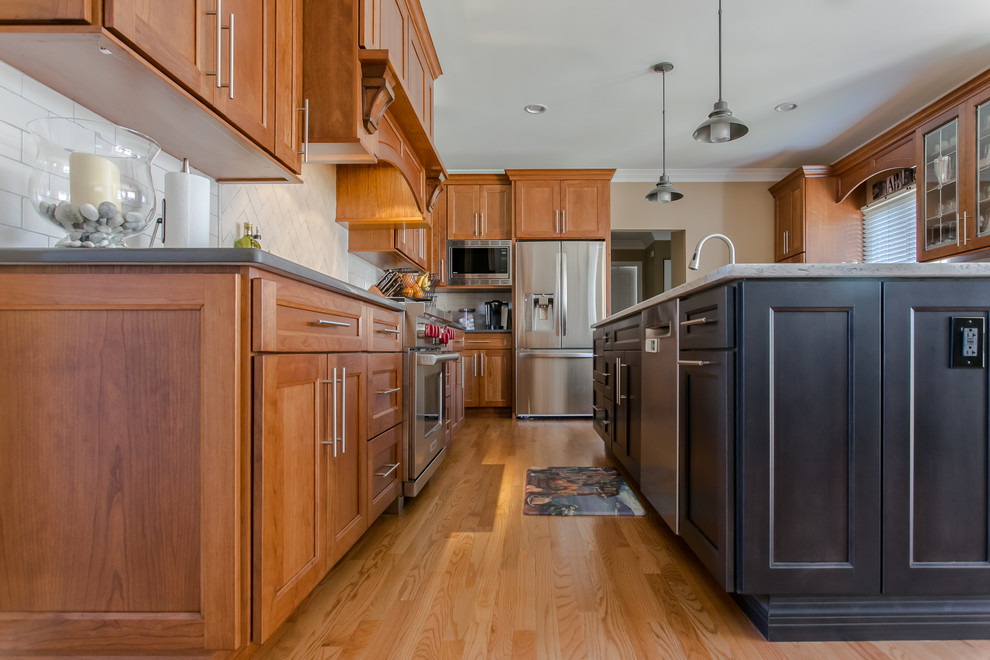Bild på ett mellanstort amerikanskt flerfärgad flerfärgat kök, med en undermonterad diskho, skåp i shakerstil, skåp i mellenmörkt trä, bänkskiva i kvarts, vitt stänkskydd, stänkskydd i tunnelbanekakel, rostfria vitvaror, mellanmörkt trägolv, en köksö och brunt golv