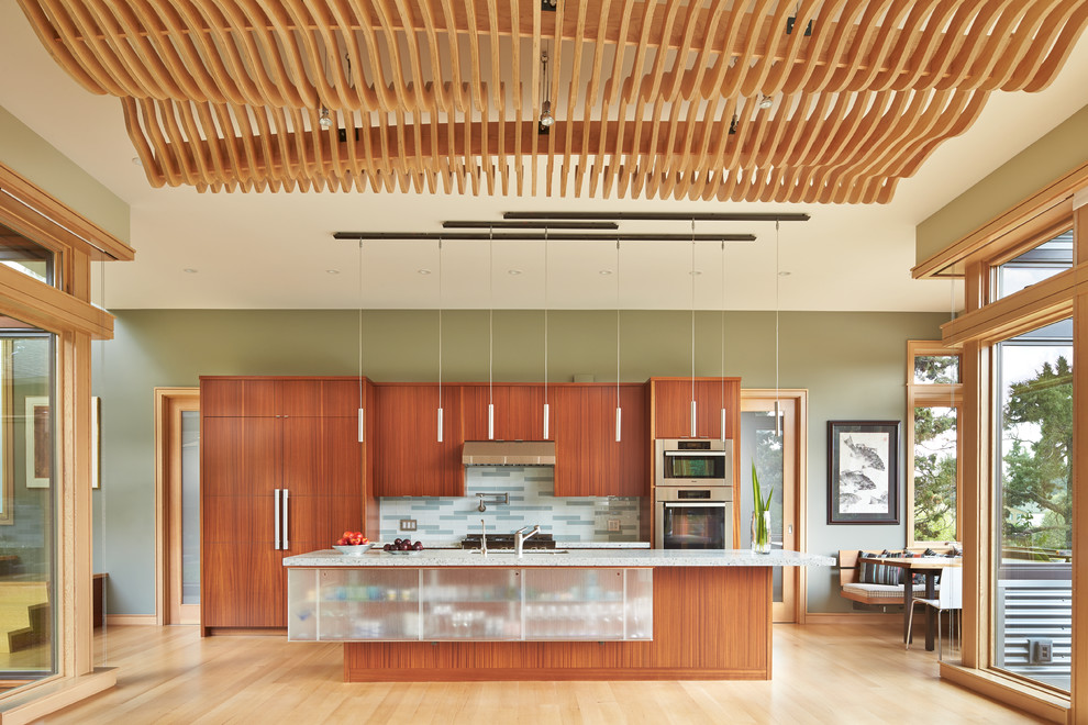 Trendy single-wall light wood floor open concept kitchen photo in Other with flat-panel cabinets, medium tone wood cabinets, multicolored backsplash, mosaic tile backsplash, stainless steel appliances, an island and an undermount sink