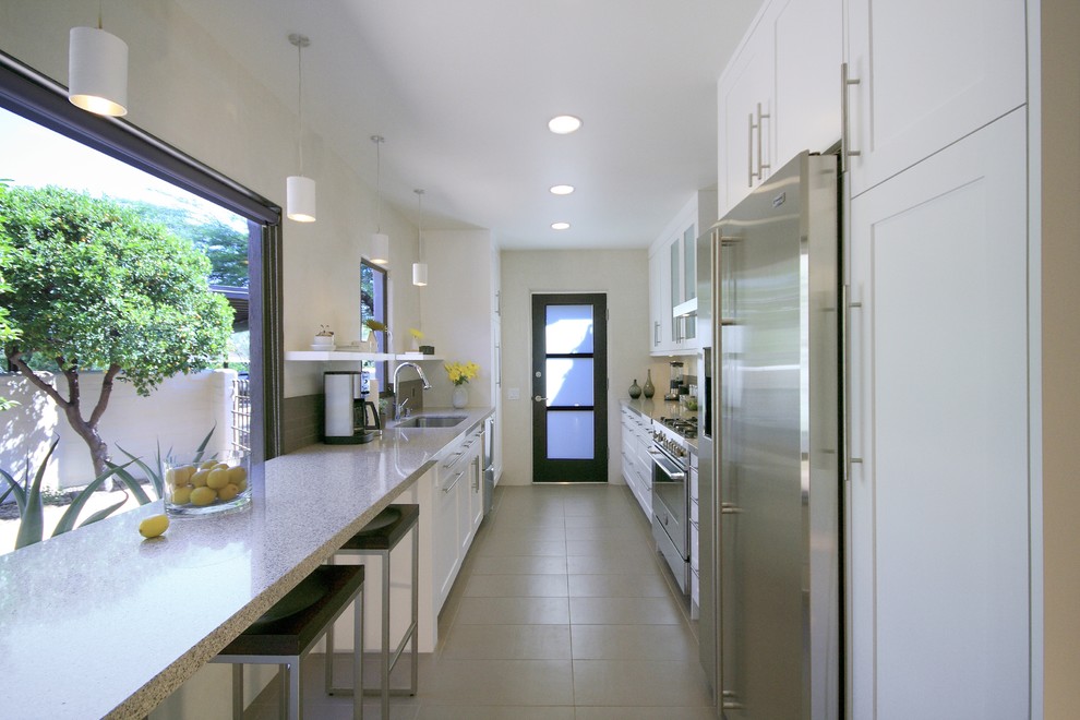 Diseño de cocina contemporánea cerrada con electrodomésticos de acero inoxidable, encimera de cuarzo compacto y barras de cocina