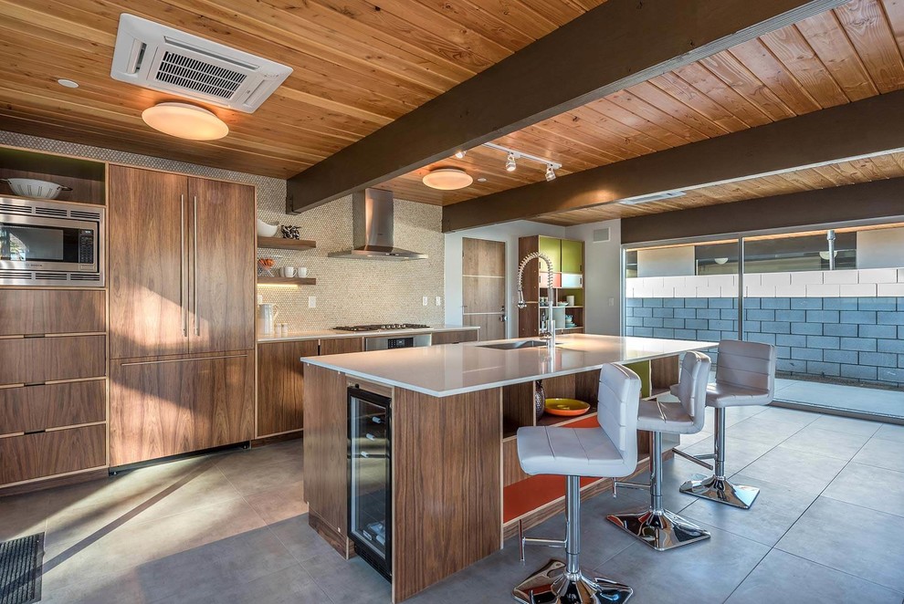This is an example of a medium sized midcentury galley enclosed kitchen in Los Angeles with a submerged sink, flat-panel cabinets, medium wood cabinets, engineered stone countertops, beige splashback, mosaic tiled splashback, integrated appliances, porcelain flooring and an island.