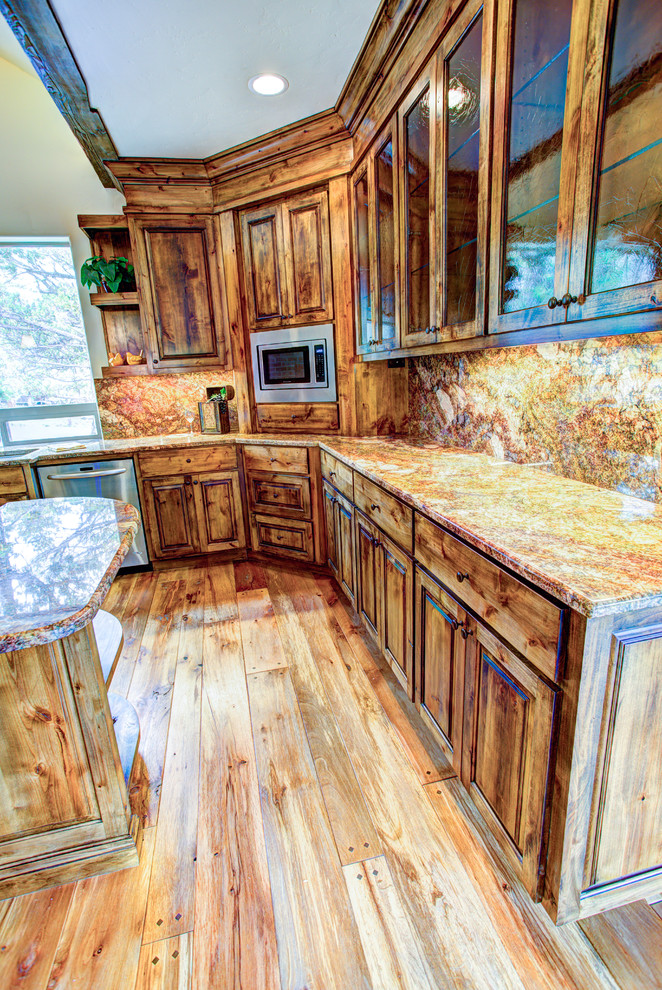 Immagine di una grande cucina rustica con lavello da incasso, ante di vetro, ante in legno scuro, paraspruzzi beige, elettrodomestici in acciaio inossidabile e pavimento in legno massello medio